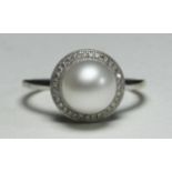 A 9k white gold ring centrally-set with a single pearl surrounded by 33 small diamonds, 2.6g