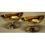 A pair of George III silver navette shape pedestal salts, engraved a crest and gilded inside, the