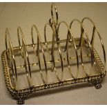 A George IV silver toastrack, the six wirework divisions with a central crested ring handle, the