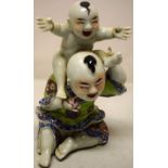 A nineteenth/twentieth century Chinese porcelain group of a seated young man, wearing a coloured