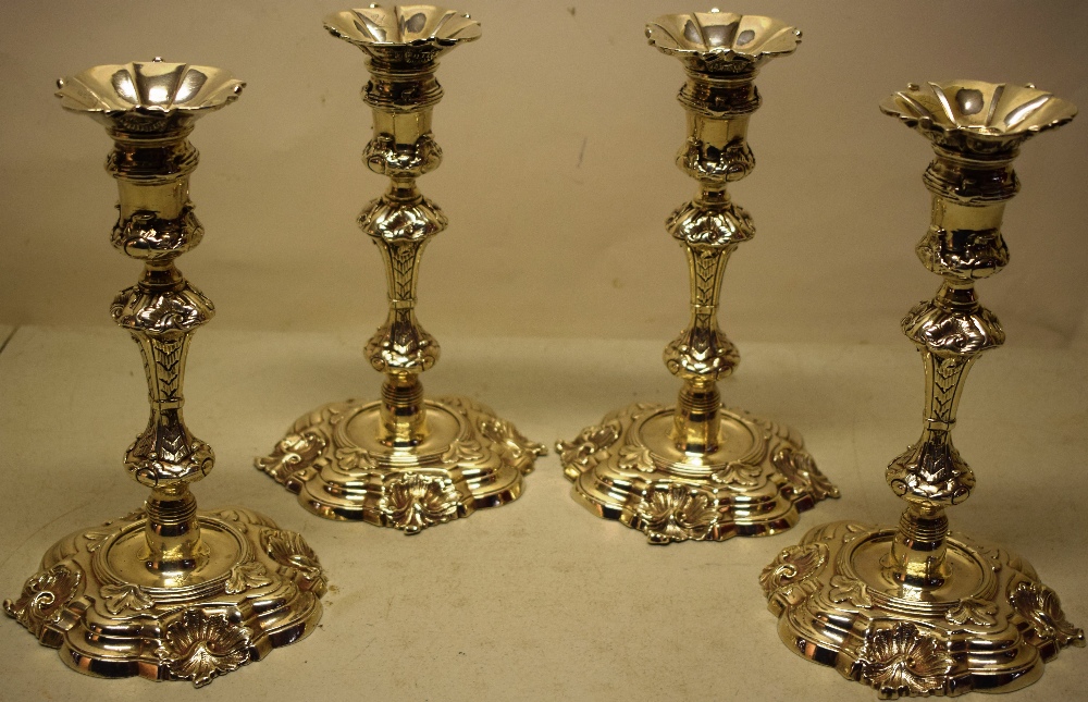 A set of four George IV cast silver candlesticks, in the manner of Paul De Lamerie, crested the