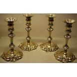 A set of four George IV cast silver candlesticks, in the manner of Paul De Lamerie, crested the