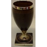 A George III coconut cup, with a silver lining and rim, on a knopped turned wood stem, a turned wood