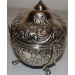 A late Victorian silver string box, with scrolling repousse foliage and vacant cartouches to the urn
