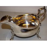An oval silver sauceboat, with a fret outline border, a moulded capped cast scroll handle, on