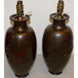 A pair of nineteenth century Japanese bronze vases, the bodies with red highlights to the
