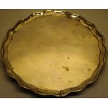 A George III silver circular salver, with a beaded serpentine raised border (old repairs) on three