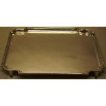A silver salver, rectangular, with a raised moulded border with serpentine corners, on splay feet,