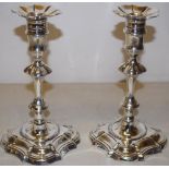 A pair of George II cast silver candlesticks, the spool shape candleholders with nozzle