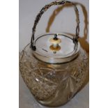 An Edwardian cut glass biscuit barrel, with silver rim, a pierced decorated swing handle and a