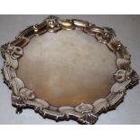 An Edwardian silver card waiter in George III style, with a raised moulded shell scroll border, on