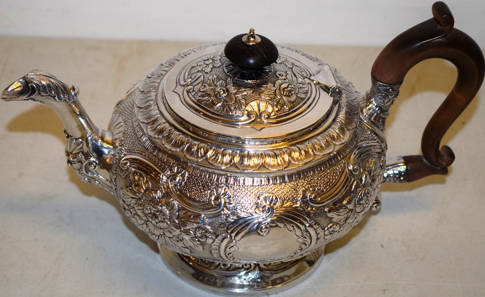 A Regency silver teapot with chased floral scrolls, vacant cartouches, a cast leaf capped mask set