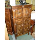An Old Charm type Oak Drinks Cabinet having two pairs of raised and fielded panelled doors with