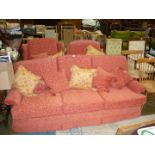 A Terracotta coloured three piece lounge suite comprising a three-seater settee and a pair of wing