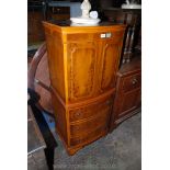 A bow-fronted Yew wood finished cocktail cabinet having a pair of opposing doors to the top