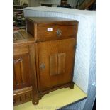 An Oak finished bedside Cabinet with linen-fold in relief to the door and with a frieze drawer over.