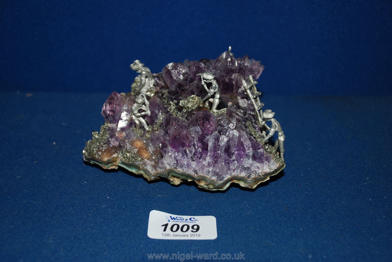 A piece of amethyst cluster having small figures chipping away