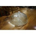 A glass cake stand with cover in spiral design.