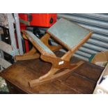 An Oak framed rocking Gout Stool having pale fawn upholstery with studded edges.