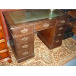 A compact early 20th Century Oak kneehole pedestal desk, having inset green leather top,