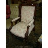 An Edwardian Walnut and other woods framed Lady's Fireside open-armed Chair with cream ground,