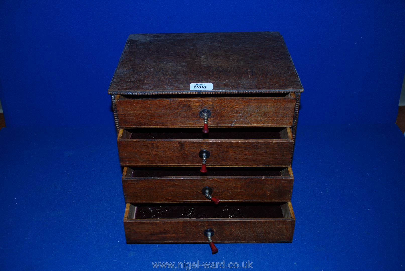 A small four-drawer wooden table top Cabinet with velvet lined drawers.