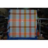 A very large travel rug/blanket in orange, blue and browns.