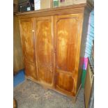 A Mahogany triple doored Wardrobe having a dentil frieze tot he pediment,