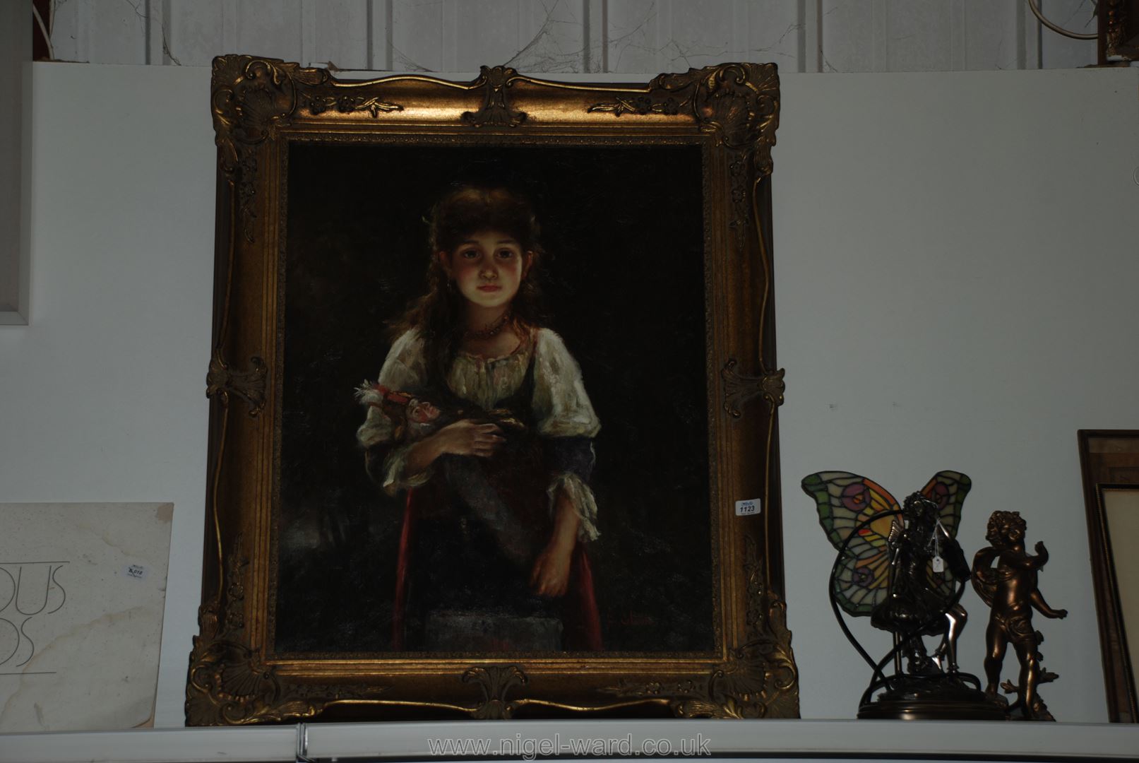 A framed reproduction illustration on canvas of a young girl holding a doll,