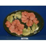An oval green Moorcroft dish with Hibiscus decoration