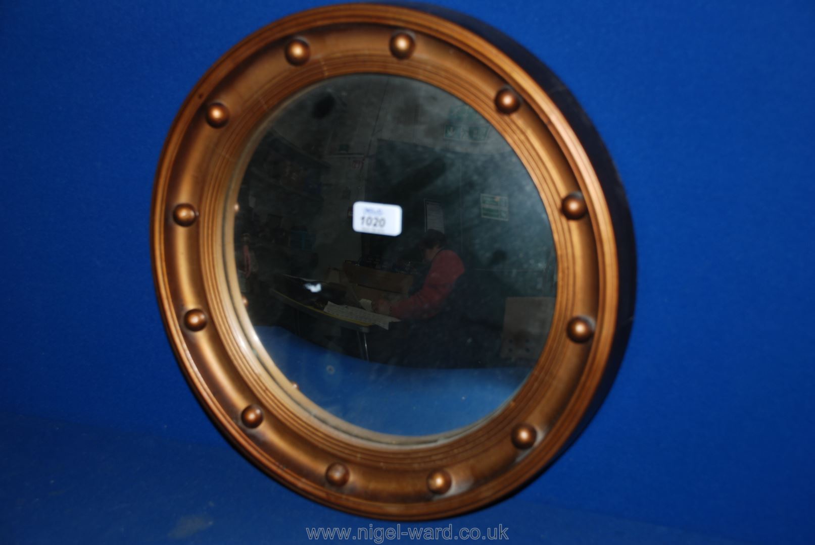 A circular convex wall mirror with a wooden framed with a gold- coloured rim.