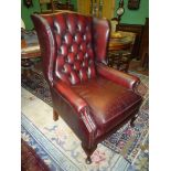 A burgundy leather upholstered button back wing Fireside Chair on brief cabriole front lets,