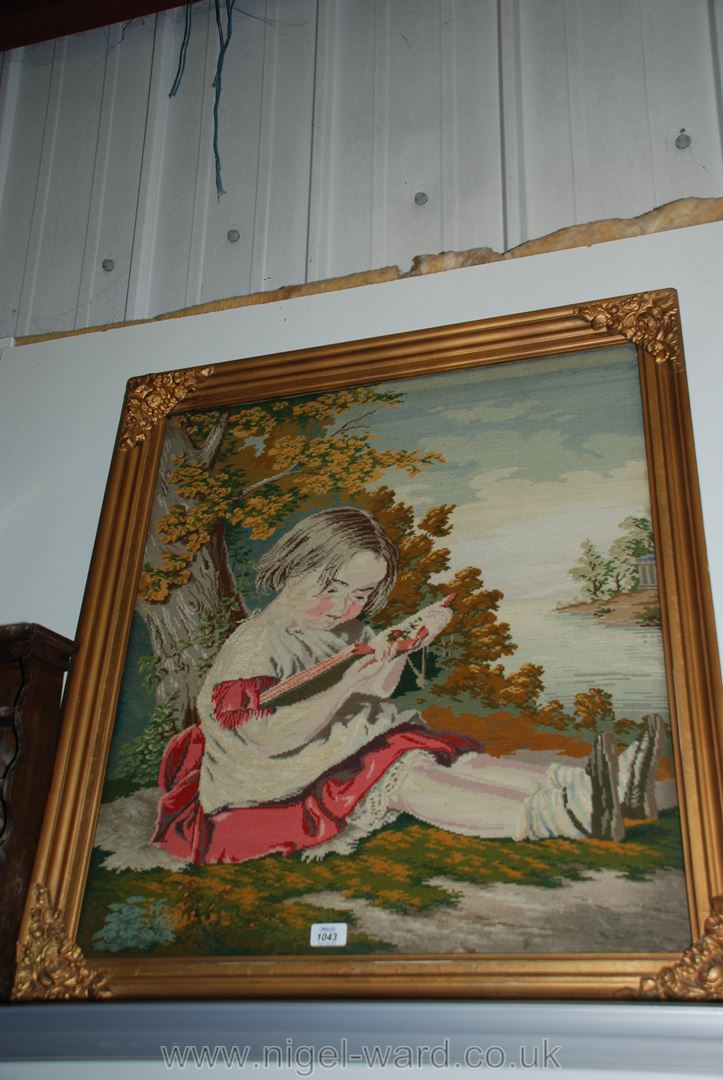 A Victorian Woolwork embroidery picture of a young girl reading under a tree,