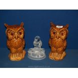 A pair of brown glass eyed owls and a glass owl paperweight.