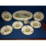 A large fish serving dish and six plates decorated with fish and a sauce jug with a chip on the