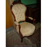 A Mahogany framed buttoned back open armed Lady's Armchair having carved flowers and foliage to the