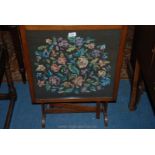 An Oak framed metamorphic Firescreen/Table, the panel decorated with a hand worked tapestry,