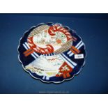 An Imari plate with scalloped rim and blue rings to base.