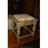 A matt finished Oak framed Stool with drop-in floral upholstered seat and standing on turned legs