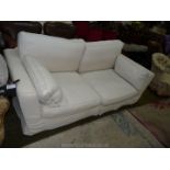 A cream/off-white loose covered three seater Settee