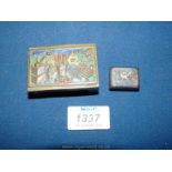 An enamel decorated brass matchbox holder depicting in relief plants in vases, a trivet, etc.