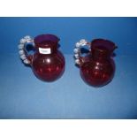 Two cranberry glass Jugs, having clear glass handles, 7" tall.