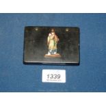 A lacquered Tobacco Box having a religious figure depicted in polychrome colours to the hinged lid,