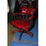 A burgundy buttoned leather upholstered swivel Study Chair on five splay feet base and having