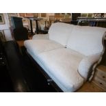 A WHITE UPHOLSTERED TWO SEATER SOFA