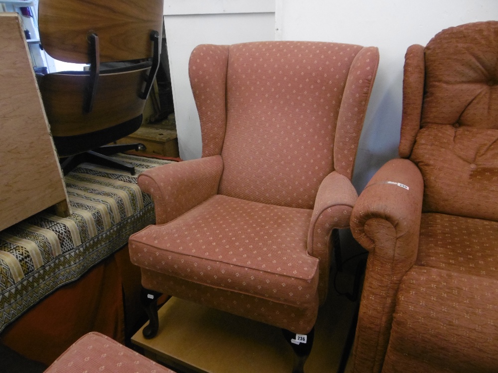 An upholstered wing armchair and stool,