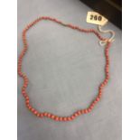 A coral bead necklace with yellow metal clasp