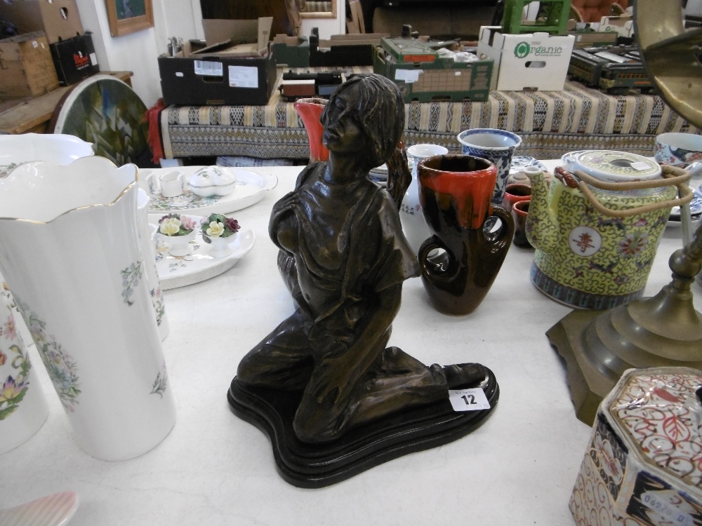 A bronze sculpture of a kneeling lady on marble plinth