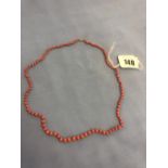 A coral bead necklace with yellow metal clasp