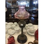 A Victorian oil lamp with cranberry shade